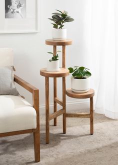 two wooden tables with plants on them in front of a white chair and window sill