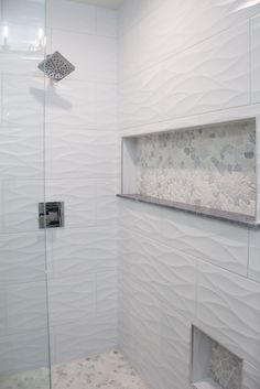 a walk in shower sitting next to a white tiled wall