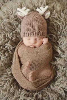 a newborn baby wearing a knitted deer hat and blanket