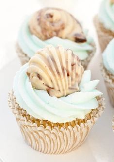 three cupcakes with white frosting and chocolate chip cookies on top are sitting on a plate