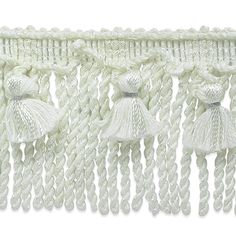 white tasselled trim with fringes and beads on the ends, attached to a wall