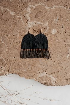 two black tassels hanging from the side of a stone wall next to dry grass