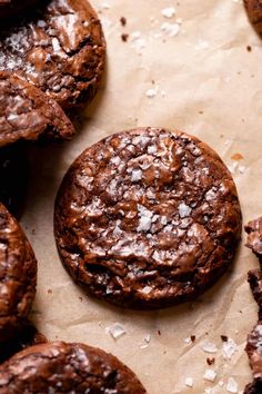 chocolate cookies with sea salt sprinkled on top are sitting on parchment paper and ready to be eaten