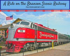 a red and silver train traveling down tracks next to a flag on top of a building