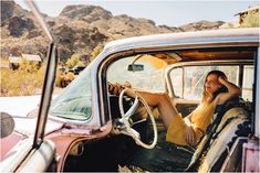 a woman sitting in the driver's seat of an old car with her feet on the dashboard