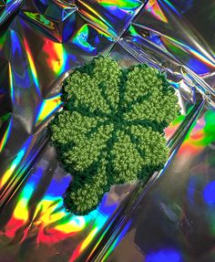 a green piece of broccoli sitting on top of a shiny surface