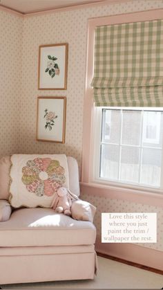 a pink chair in front of a window with some pictures on the wall behind it