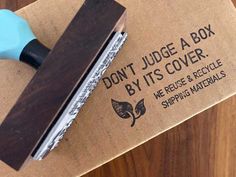 a rubber stamper sitting on top of a brown cardboard box next to a piece of paper that says, don't judge a box by its cover