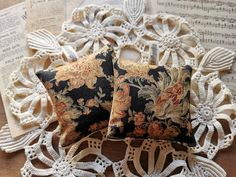 two decorative pillows sitting on top of a doily next to an old sheet of music