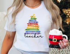 a woman wearing a teacher shirt holding a coffee mug