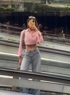 a woman taking a selfie in front of an escalator with her cell phone