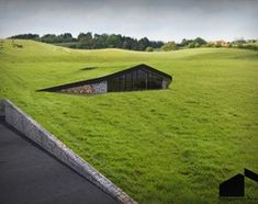 an unusual house in the middle of a green field