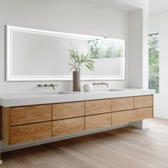 a bathroom with two sinks and a large mirror on the wall over it's windows