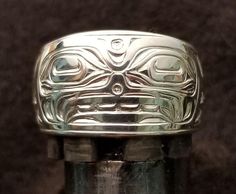 On offer is a West Coast Namgis First Nation Hand Carved Sterling Silver ''Orca'' ring. by World renowned master carver Joe R. Wilson with his depiction of Orca in the style of the Namgis, Kwakiutl First Nation. Initialed by Joe. Fine example of Indigenous Art from the Northwest Coast First Nations of Canada. PLEASE NOTE THAT THIS IS A CUSTOM RECREATED HAND CARVED ITEM THAT WILL HAVE SLIGHT, SUBTLE DIFFERENCES THAT ARE VERY HARD TO DISTINGUISH WHEN COMPLETED FROM THE PICTURES SHOWN ABOVE! DO NOT Symbolic Carved Jewelry For Formal Occasions, Artisan Carved Rings, Artisan Rings With Polished Finish For Formal Events, Artisan Rings With Polished Finish For Formal Occasions, Artisan Rings With Polished Finish For Collectors, Custom Engraved Ring With Polished Finish, Winter Ceremony, Killer Whale, Secret Society