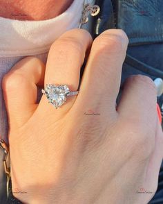 a close up of a person's hand wearing a ring with a diamond on it