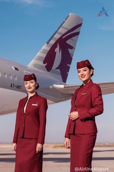 two women in red uniforms standing next to an airplane