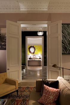 an open door leading to a living room with yellow walls and artwork on the wall