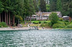 a large house sitting on top of a lush green hillside next to a body of water