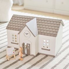 a small toy house with a clock on the front and two children's toys next to it