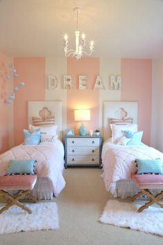 two twin beds in a bedroom with pink and white striped walls, chandelier and rugs