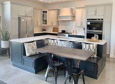 a large kitchen with an island in the middle and chairs at the counter top,