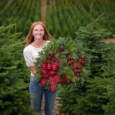 a woman holding a wreath in a christmas tree farm