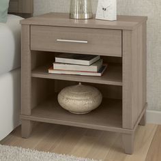 a night stand with books and a vase on it