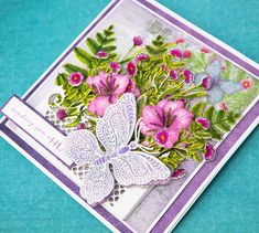 a close up of a card with flowers and a butterfly on the front, sitting on a blue surface