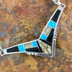 This gorgeous Sterling Silver Necklace shown in the Turquoise Creek Collection, features Black Jade, Picture Jasper, and Kingman Turquoise. Dimensions:1"T x 2 1/2"W w/ 14" Omega Chain They are designed by David Rosales, one of the finest contemporary Southwest Artists in the world. He is the founder and co-owner of Supersmiths, Inc. of Gallup, NM. This Handcrafted Necklace is custom made and carries a lifetime guarantee. In the event that this item is in stock in our Prescott store, we will ship it within 2 business days. Otherwise, Please allow 3-4 weeks for delivery. Note: Prices are subject to change with fluctuations in the price of silver. If you need a rush order or are interested in Yellow or White Gold please call 1.800.621.6668. Unique Blue Necklace With Inlay, Unique Blue Turquoise Inlay Necklace, Turquoise Pendant Necklace With Inlay, Southwestern Blue Necklace With Inlay, Artisan Blue Inlay Necklaces, Southwestern Blue Inlay Necklace, Southwestern Style Blue Inlay Necklace, Collectible Blue Inlay Necklace, Artisan Blue Turquoise Necklace With Inlay