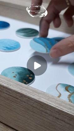 a person is pointing at some blue and white circles on a wooden surface with their finger