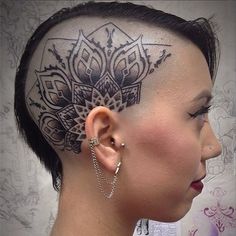 a woman with a shaved head has an intricate tattoo design on it's forehead