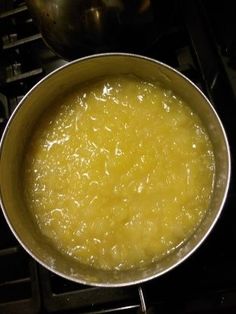 a pan filled with yellow liquid sitting on top of a stove next to an oven