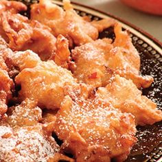 a close up of food on a plate with powdered sugar and an apple in the background