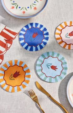 colorful plates and forks on a white table cloth