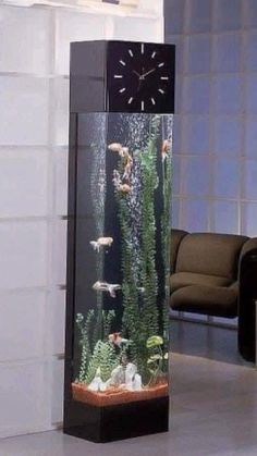 an aquarium with plants and fish in it is displayed on the floor next to a chair