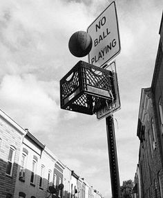 black and white photograph of a street sign with a ball in the basket on it