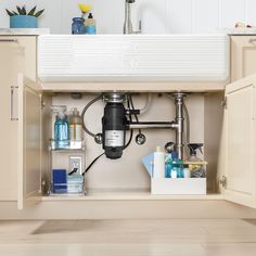 a kitchen sink under a faucet filled with bottles and other household care items