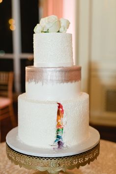 a three tiered white wedding cake with frosting and flowers on the top layer