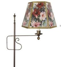 a lamp that is sitting on top of a table next to a light pole with a flowered lampshade