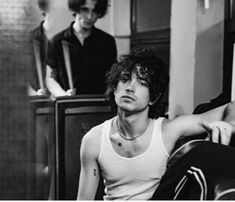 two young men sitting next to each other in front of a mirror and one is holding a guitar