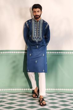 Teal blue kurta with geometric embroidered placket in cutdana, beads and mirror work. Paired with a pant.
Components: 2
Pattern: Embroidery
Type Of Work: Geometric, Beads, Cutdana
Neckline: Stand Collar
Sleeve Type: Full Sleeves
Fabric: Padma Silk
Color: Blue
Other Details: 
Embroidered buttis on kurta
Arm-hole embroidery in cutdana and beads
Note: The red kurta set worn by the other model is not for sale
Occasion: Sangeet - Aza Fashions Luxury Long Men's Kurta, Luxury Men's Winter Kurta, Luxury Men's Salwar Kameez With Resham Embroidery, Mens Mirror Work Kurtas, Luxury Men's Straight Kurta Bandhgala, Men's Luxury Long Kurta, Luxury Men's Summer Kurta, Luxury Men's Casual Kurta, Luxury Men's Churidar With Resham Embroidery