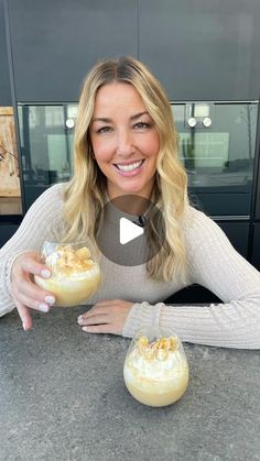 a woman sitting at a table with two desserts in front of her and smiling