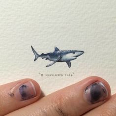 a person's hand with some nail polish on it and a drawing of a shark