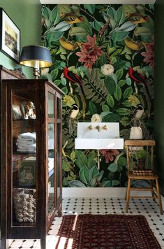 the bathroom is decorated with tropical wallpaper and green walls, along with a white sink