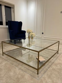 a glass coffee table with two blue chairs