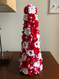 a red and white crocheted christmas tree sitting on top of a wooden table