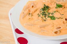 a white bowl filled with pasta and sauce on top of a polka dot tablecloth