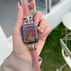 a woman holding onto a pink watch with flowers on the front and side of it