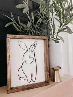 a wooden frame sitting on top of a shelf next to a vase with plants in it