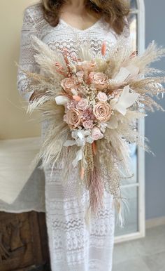 a woman in white dress holding a bouquet of flowers with feathers on the bottom and side